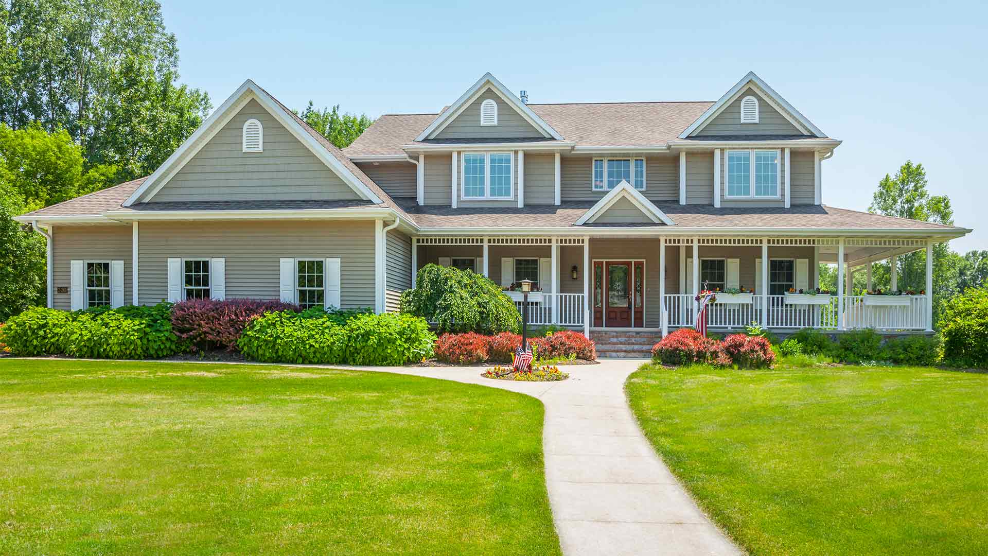 Exterior of a two-story home with a bright green lawn and covered porch