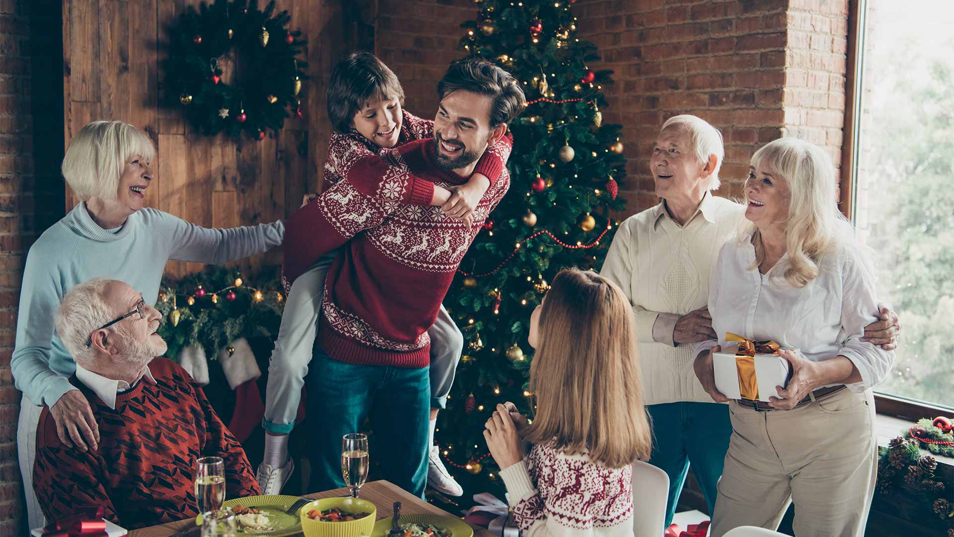 A happy family hangs out around the dinner table in their cozy living room at Christmas time