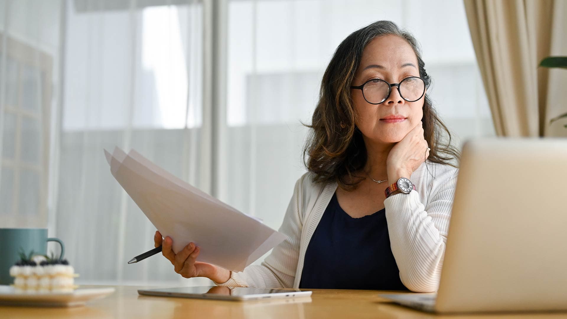 A middle-aged woman in her kitchen looks at paperwork for a home equity loan