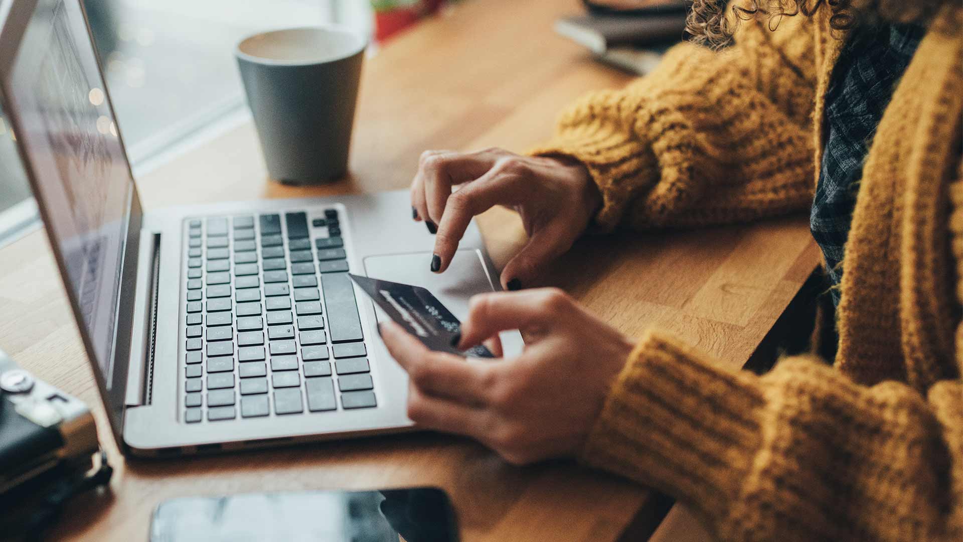 A woman looks at her credit card and her laptop weighing her options between credit cards and HELOCs