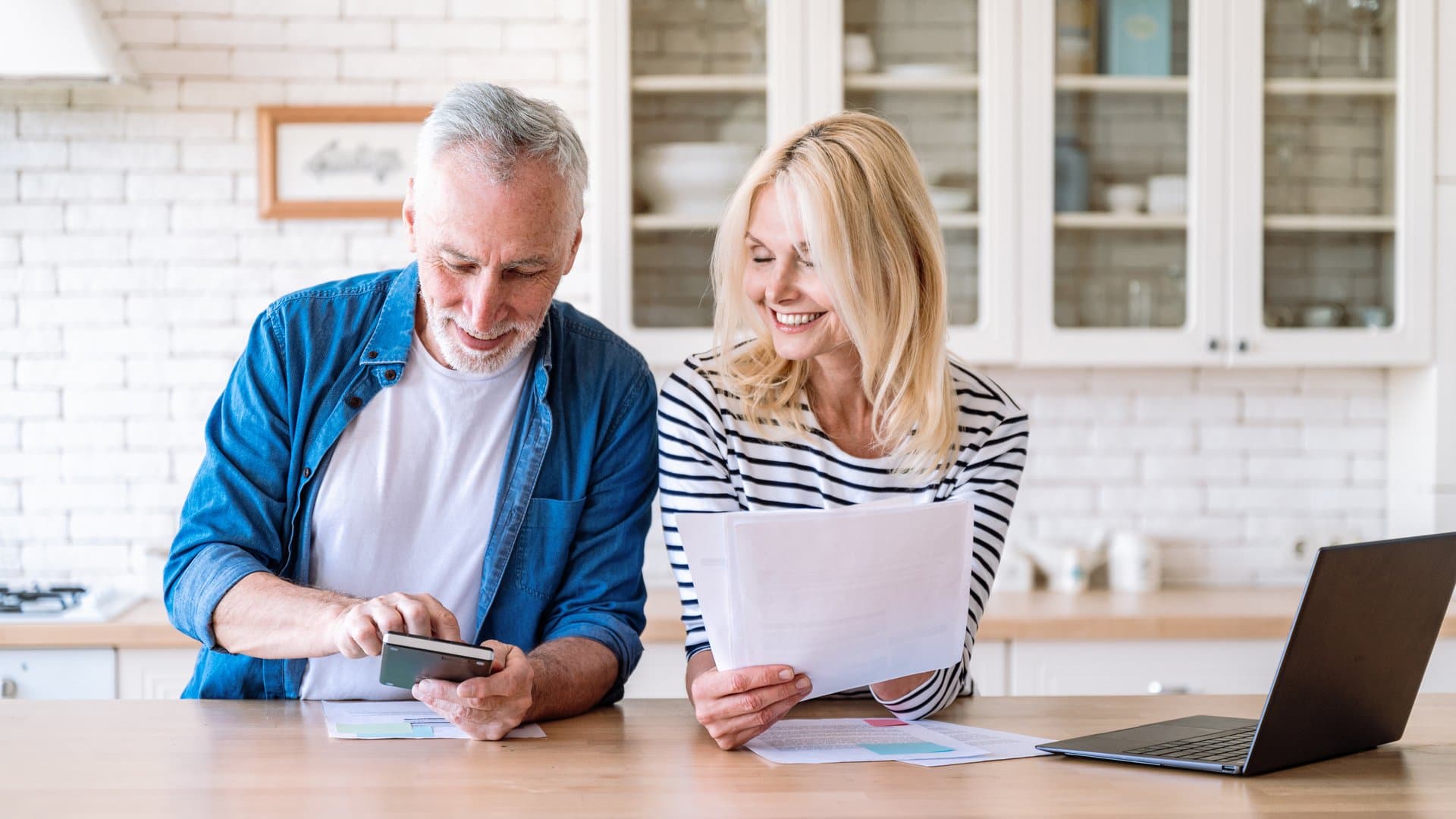 Happy retired couple managing household budget together at home