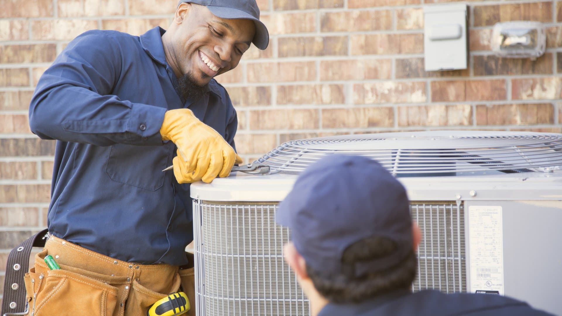HVAC technicians installing air conditioning unit at home