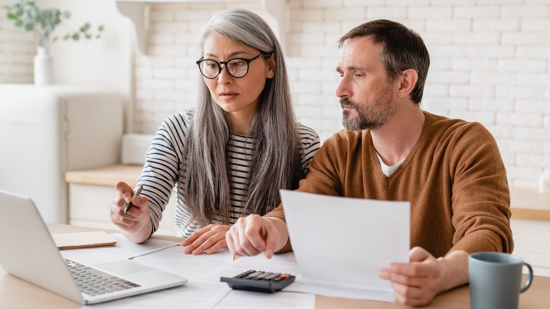 Mature couple reviewing financial documents at home